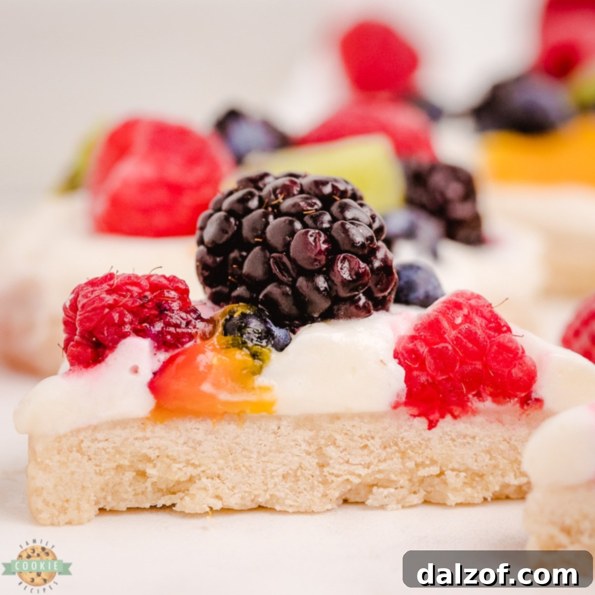 Halved fruit pizza cookies revealing layers of soft cookie, cream, and fresh berries and kiwi