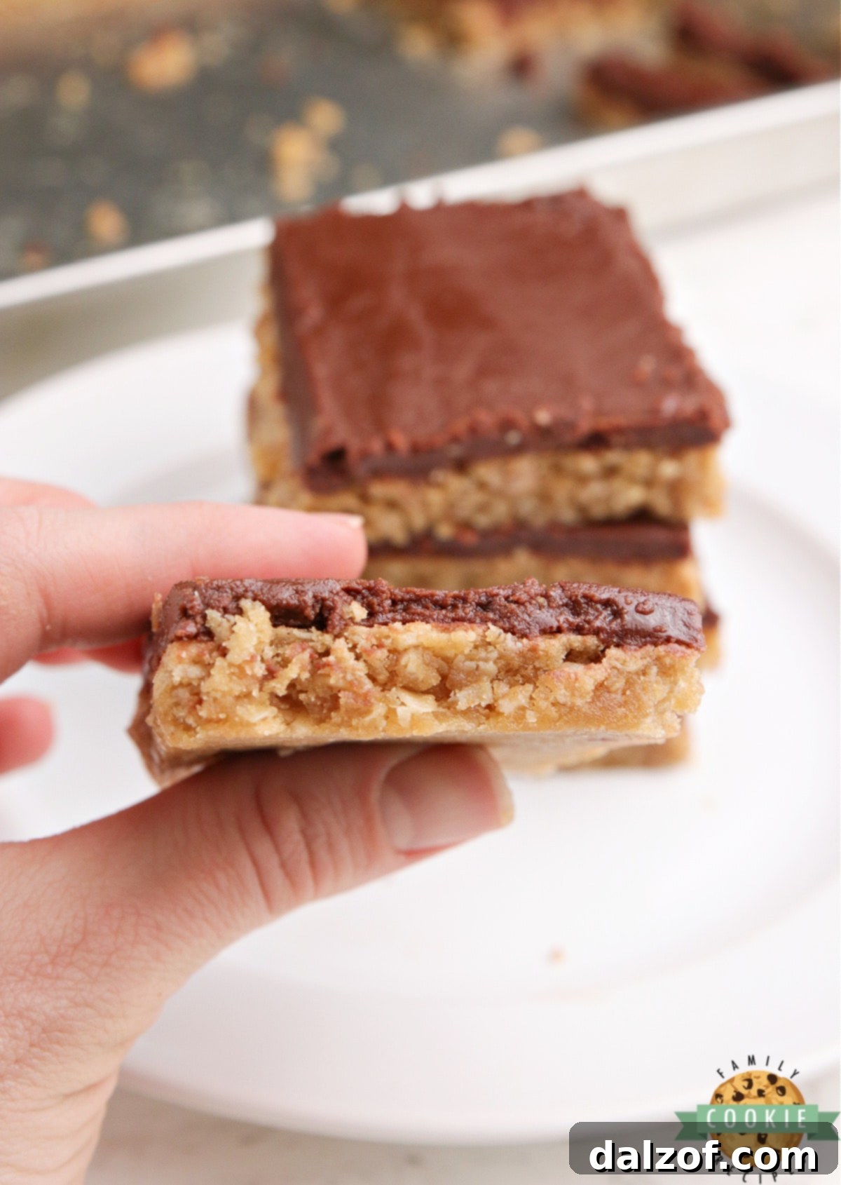 A close-up shot of the rich chocolate fudge frosting being spread over a peanut butter bar.