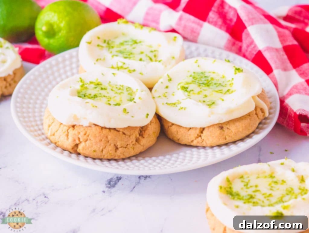 Three perfectly frosted Key Lime Pie Cookies arranged artfully on a white plate, ready to be served.