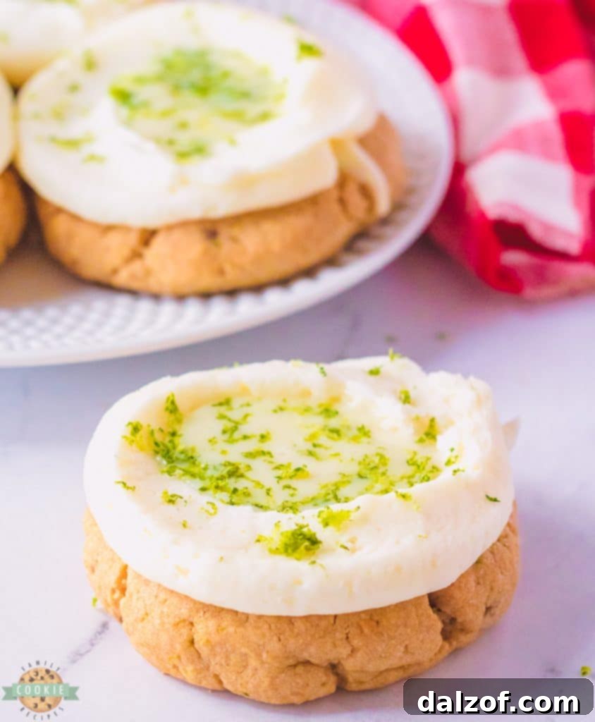 A batch of Key Lime Pie Cookies, beautifully frosted with a piped border and a dollop of lime filling in the center.