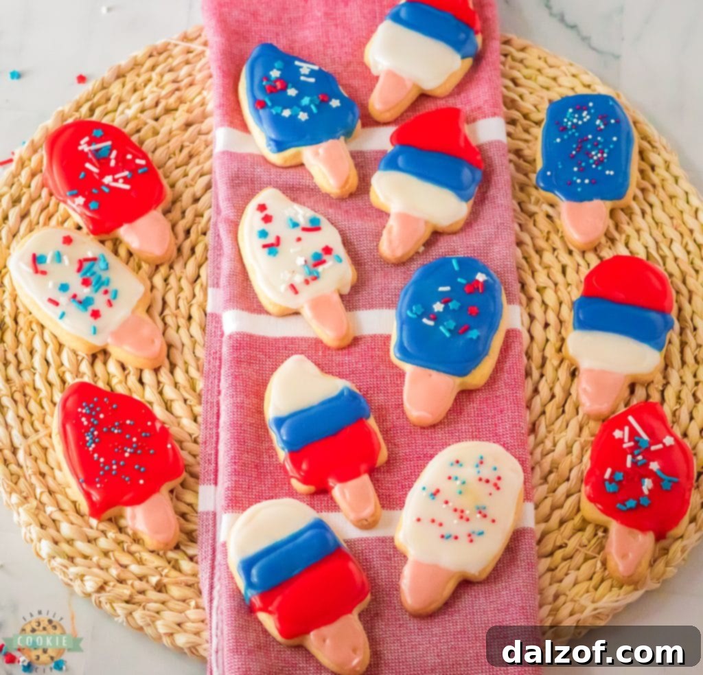 A vibrant selection of decorated popsicle sugar cookies, some with sprinkles, ready for a summer party.