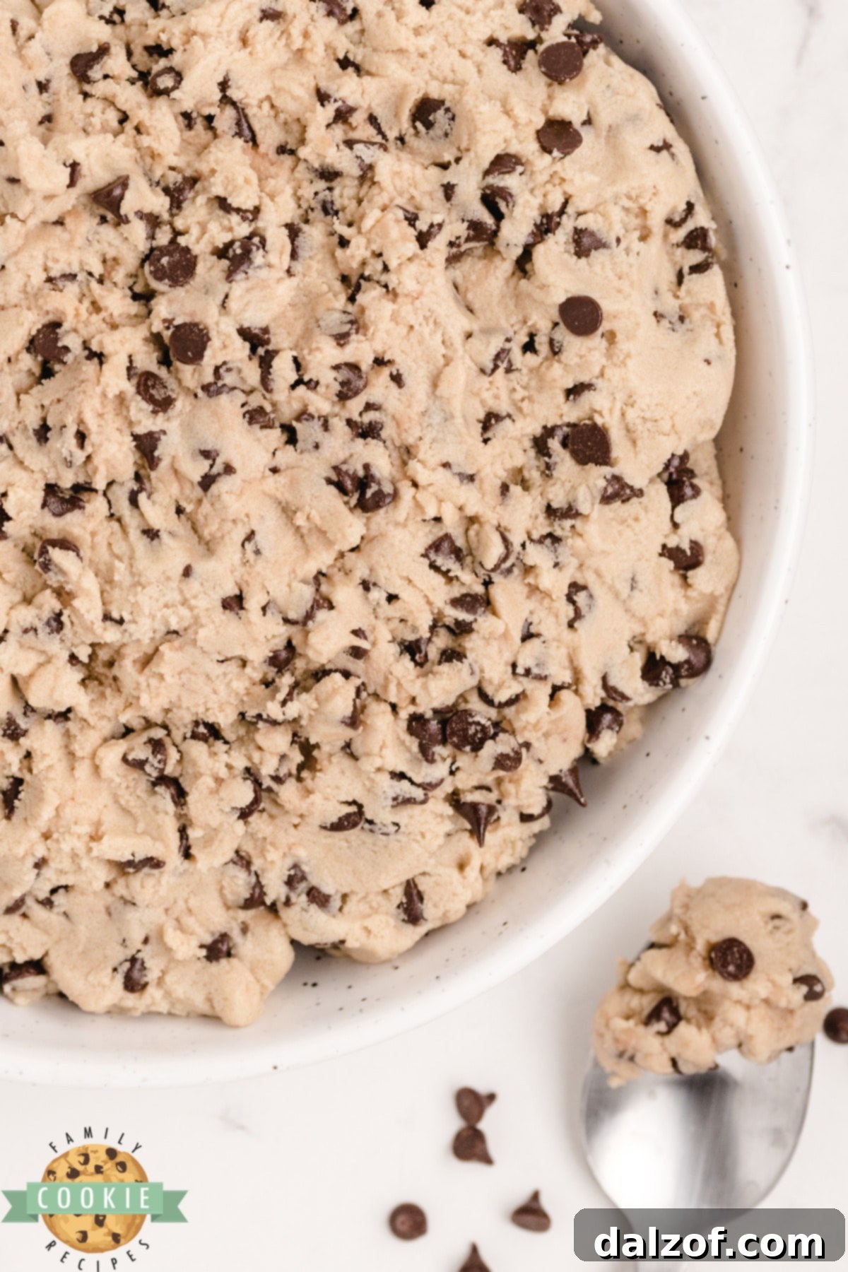 A person scooping a spoonful of safe-to-eat chocolate chip cookie dough from a mixing bowl.