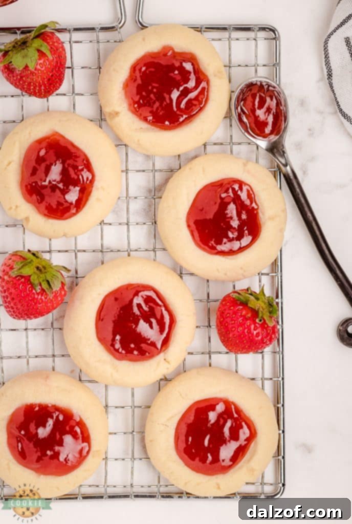 cooling rack with several strawberry thumbprint cookies on it