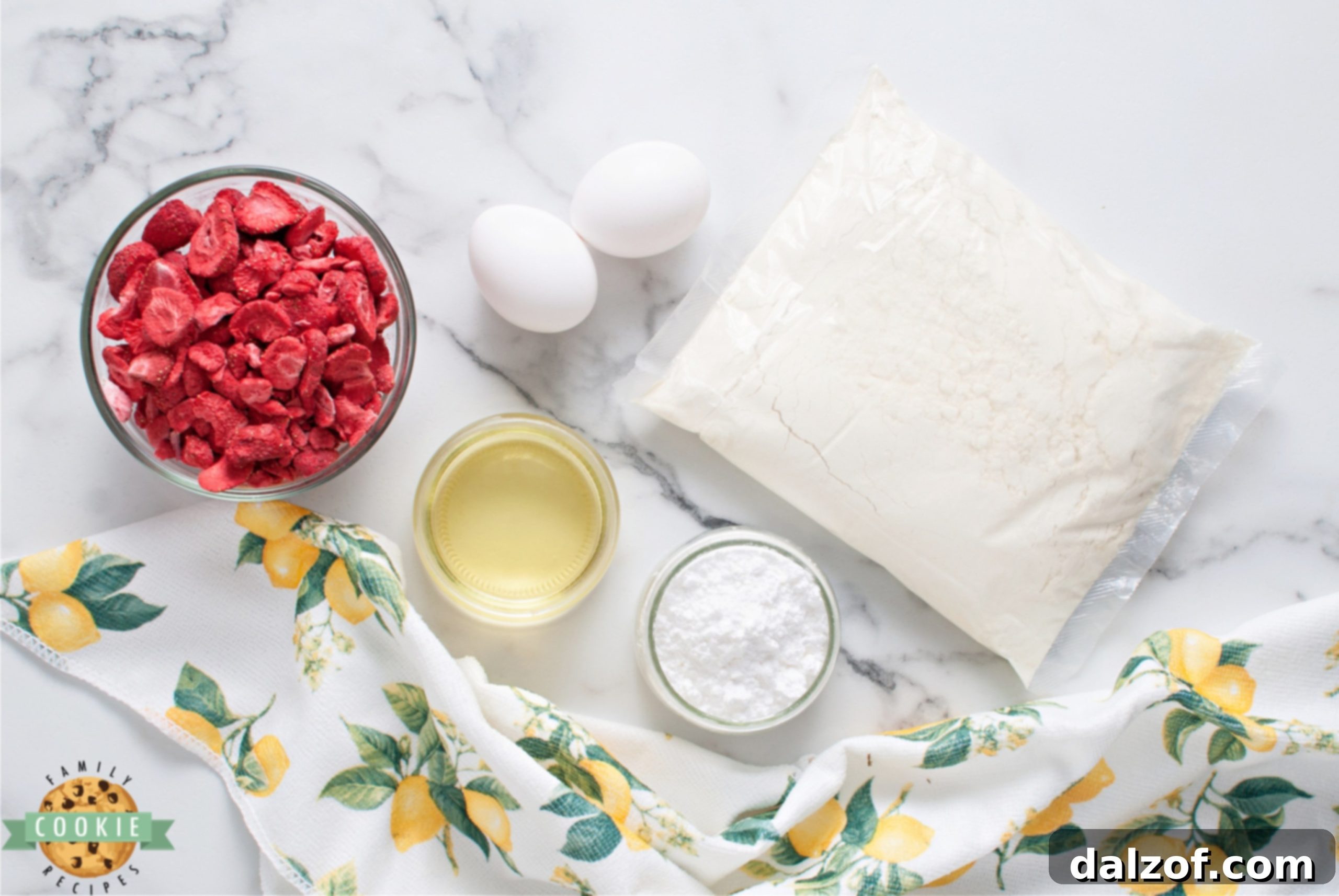 Array of essential ingredients for Strawberry Lemonade Cake Mix Cookies, including a lemon cake mix box, freeze dried strawberries, eggs, oil, and powdered sugar.