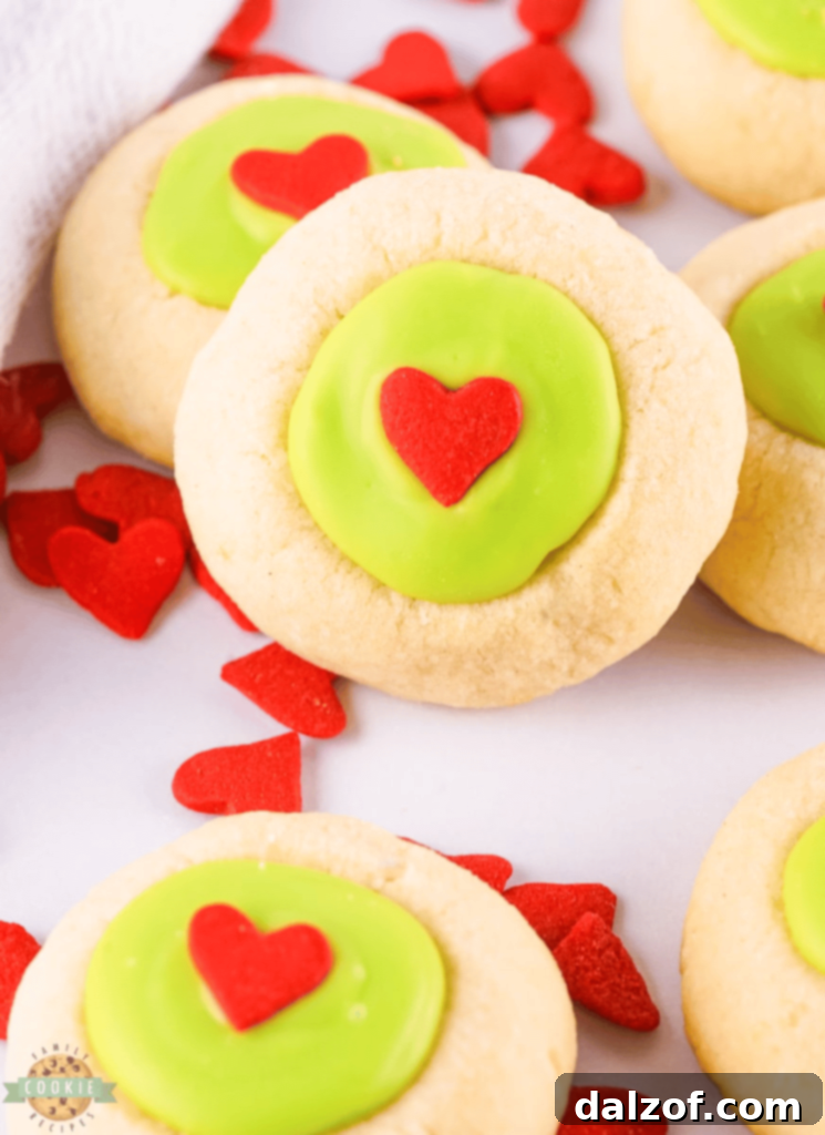 Whimsical Grinch Thumbprint Cookies with a green chocolate filling and a red heart sprinkle.