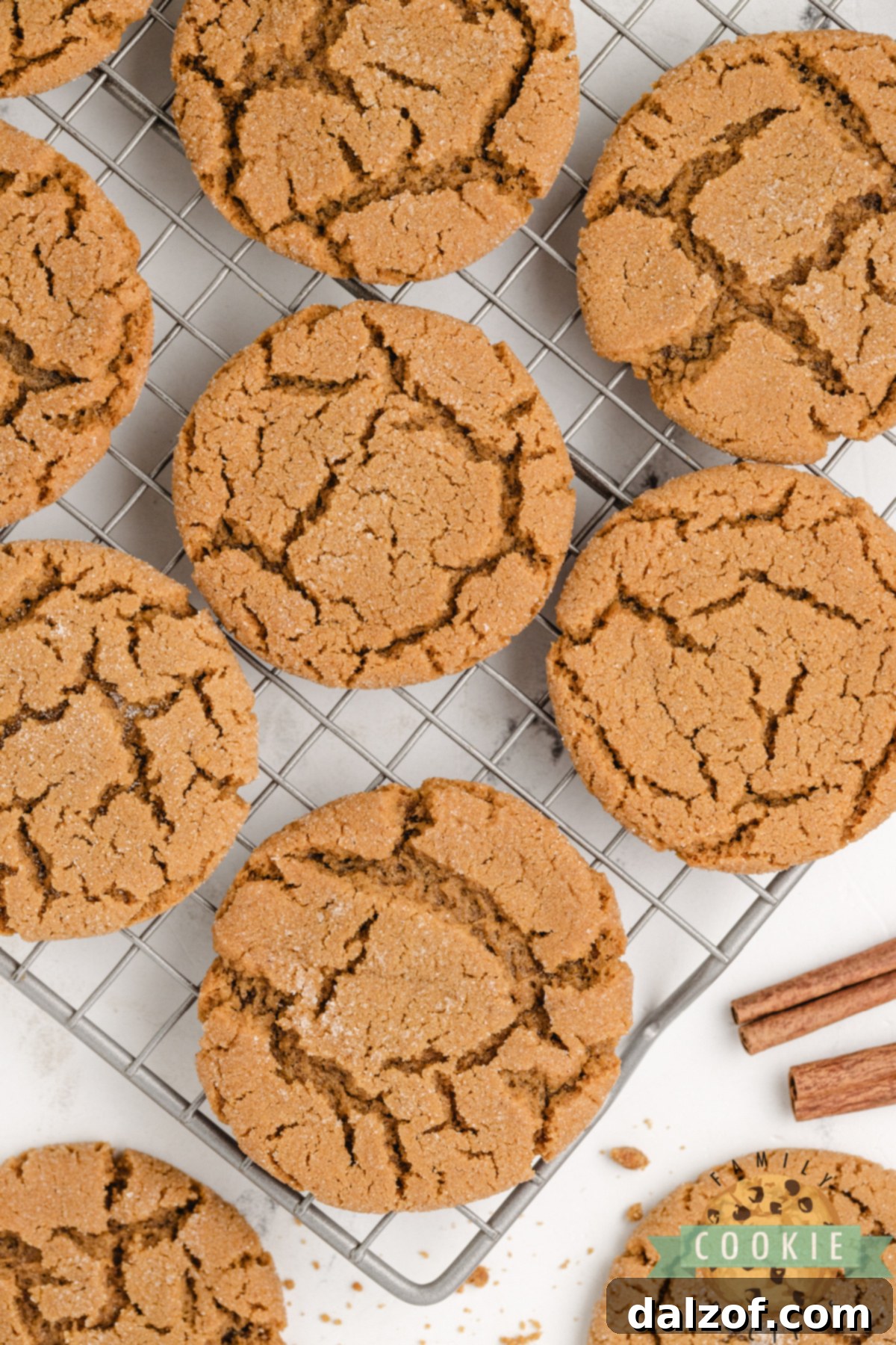 Freshly baked gingerbread cookies cooling on a wire rack with festive ribbon and cinnamon sticks nearby.