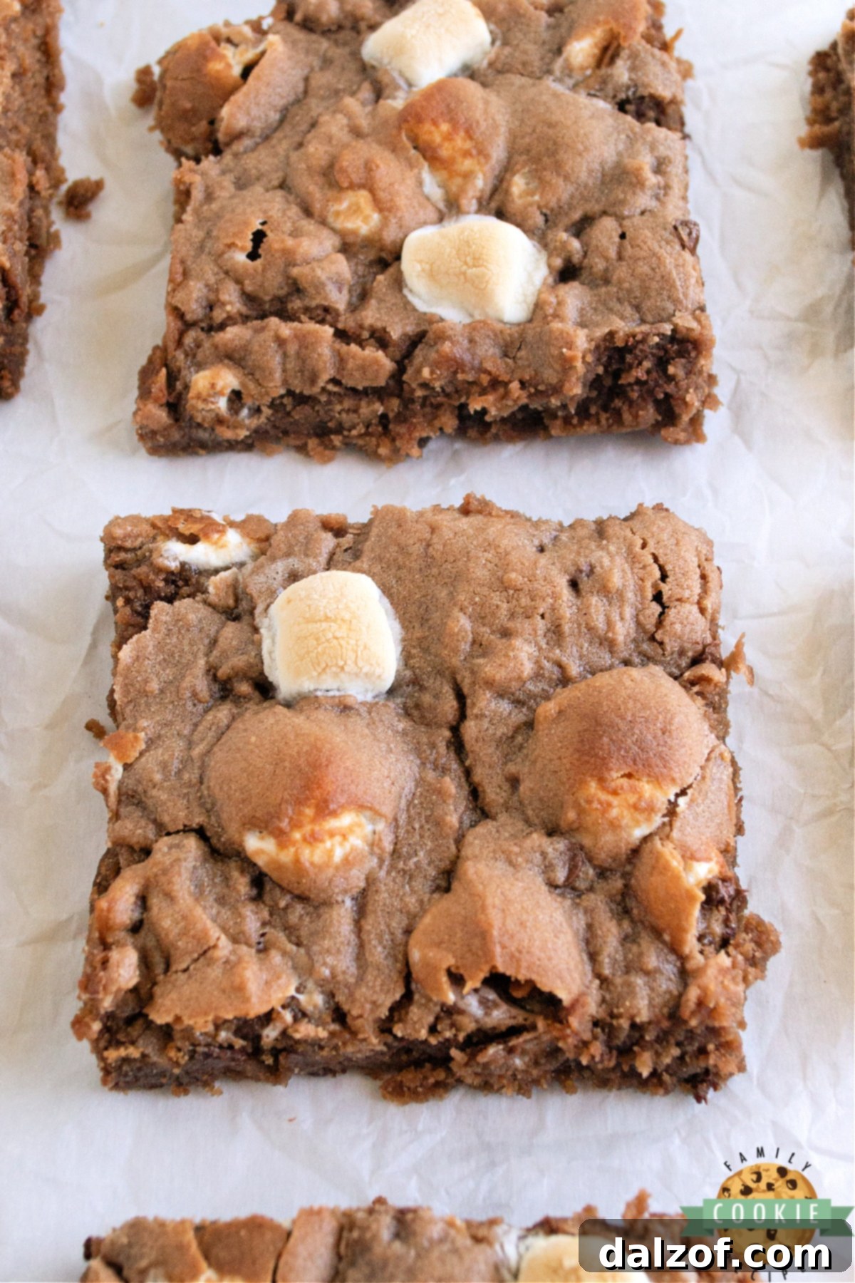 Close-up of baked hot cocoa cookie bars with melted marshmallows and chocolate chips.