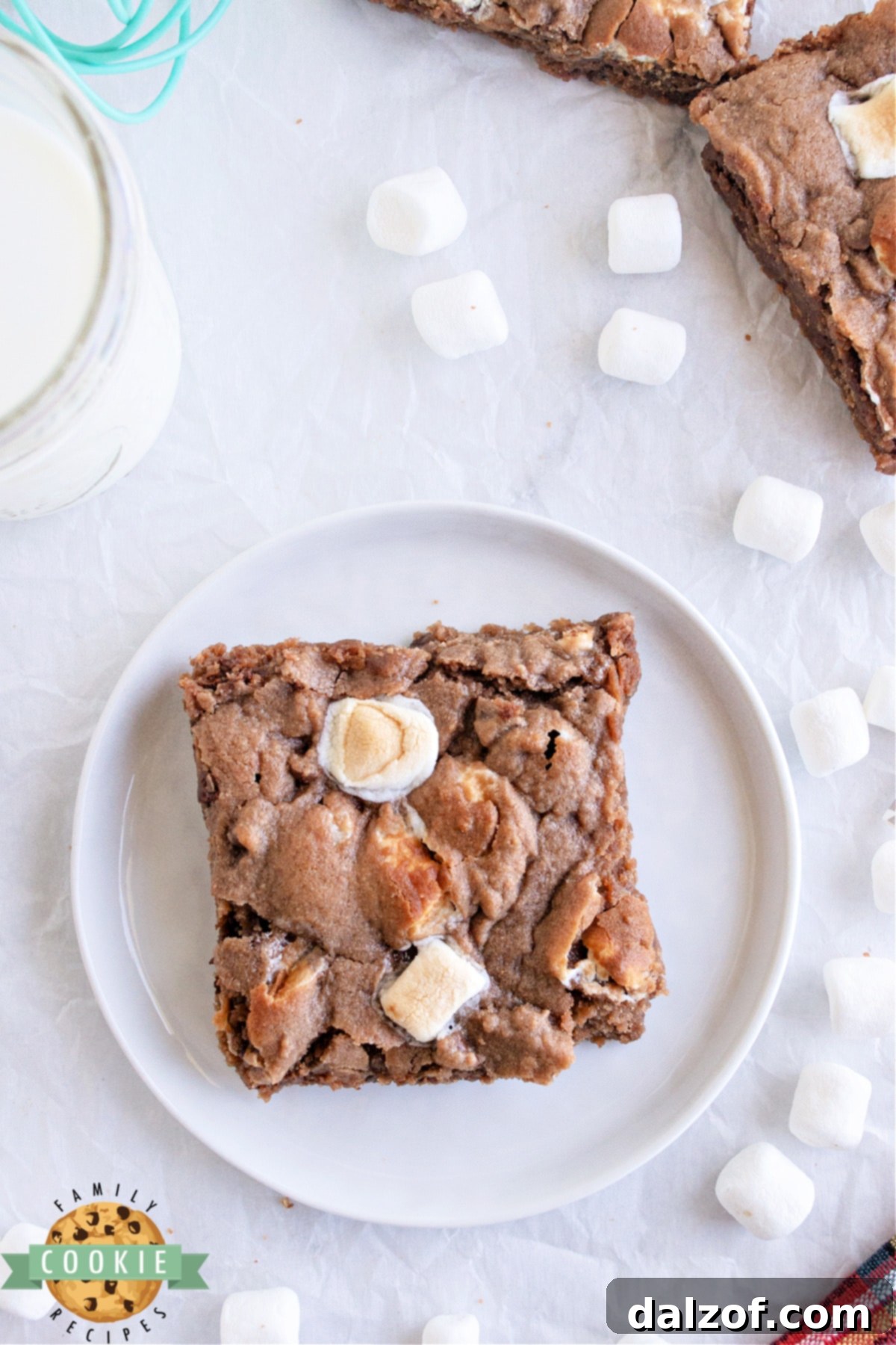 A stack of hot cocoa chocolate chip cookie bars on a white plate, ready to be served.