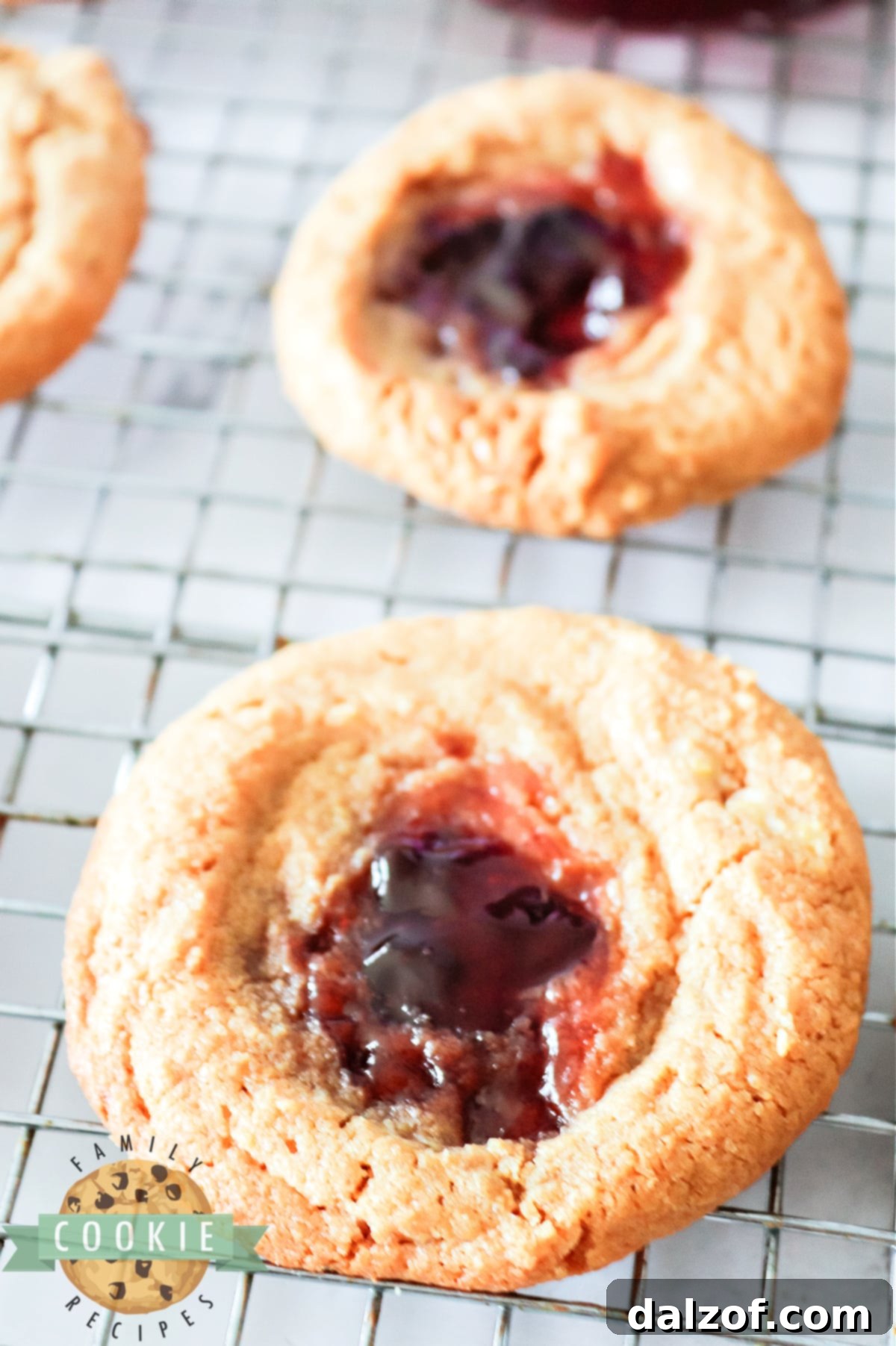 A tray of vibrant Peanut Butter and Jelly Cookies, some with golden peanut butter dough and others with darker edges, all featuring bright jelly centers.