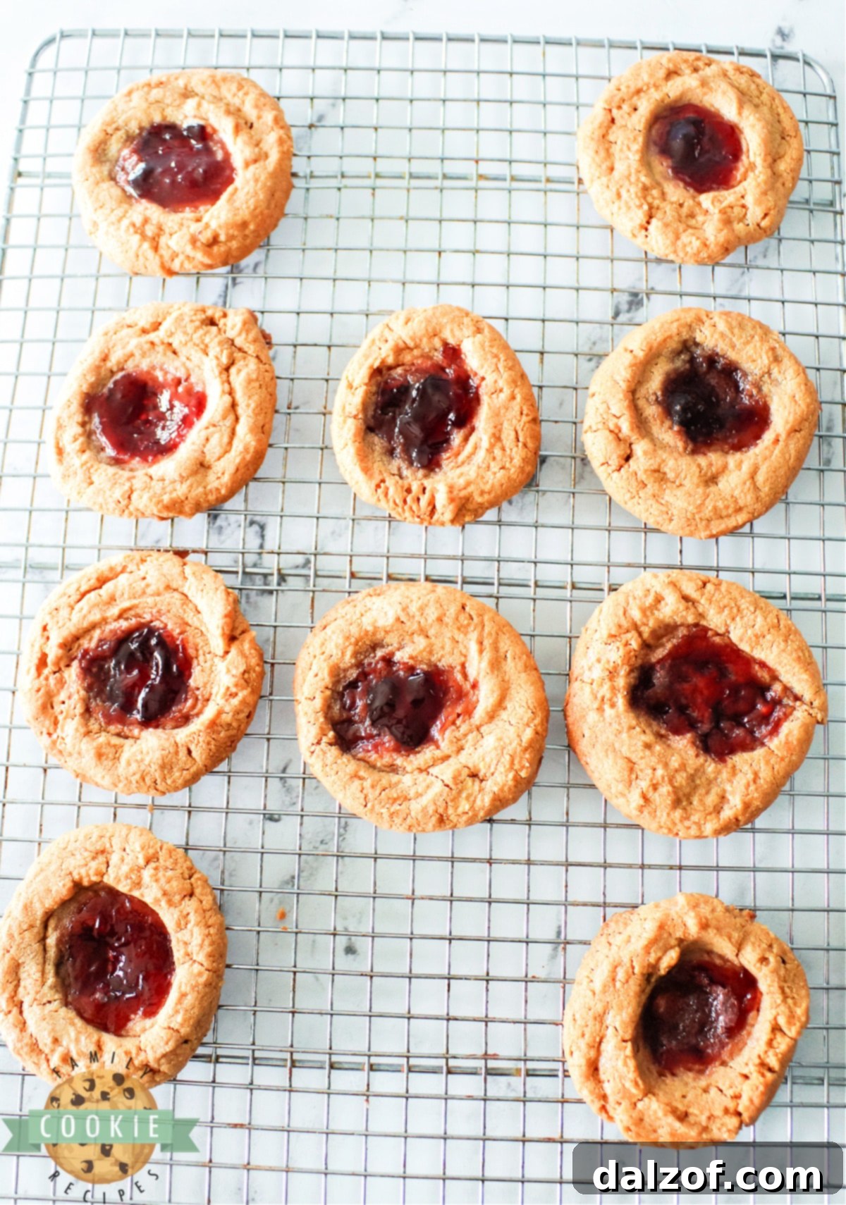 A plate of freshly baked Peanut Butter and Jelly Cookies, some with grape and some with strawberry jelly, ready to be enjoyed.