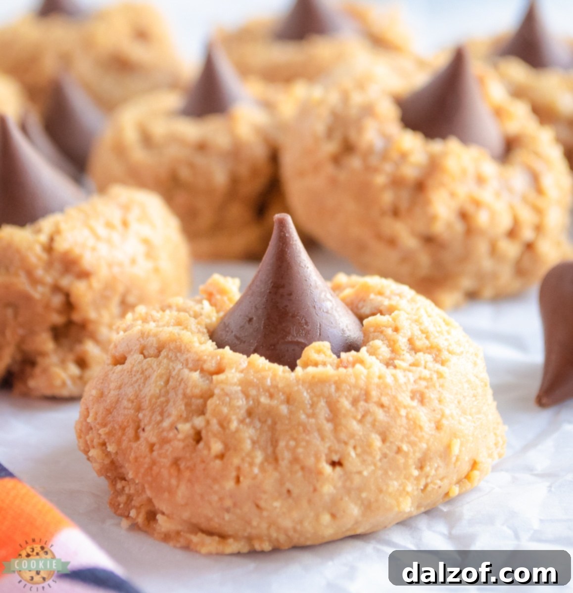 Close-up of a stack of No-Bake Peanut Butter Blossom Cookies, showcasing their soft texture and chocolate kiss tops.
