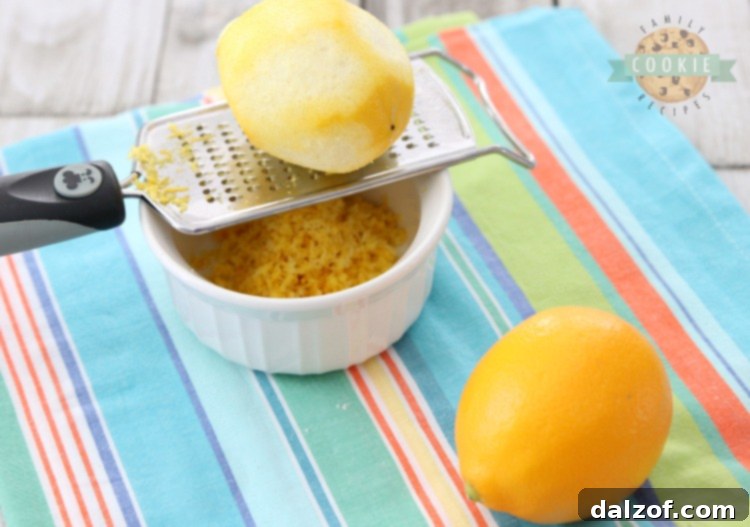 Close-up of a hand zesting a fresh lemon with a microplane grater