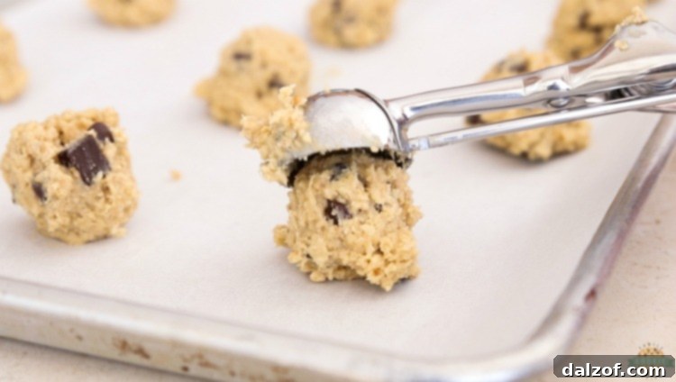 A scoop of oatmeal cookie dough ready to be placed on a baking sheet, ensuring uniform cookie size.