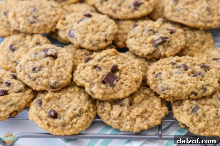 A vibrant close-up of a stack of freshly baked Chocolate Chip Oatmeal Cookies, emphasizing their rich texture and golden color.