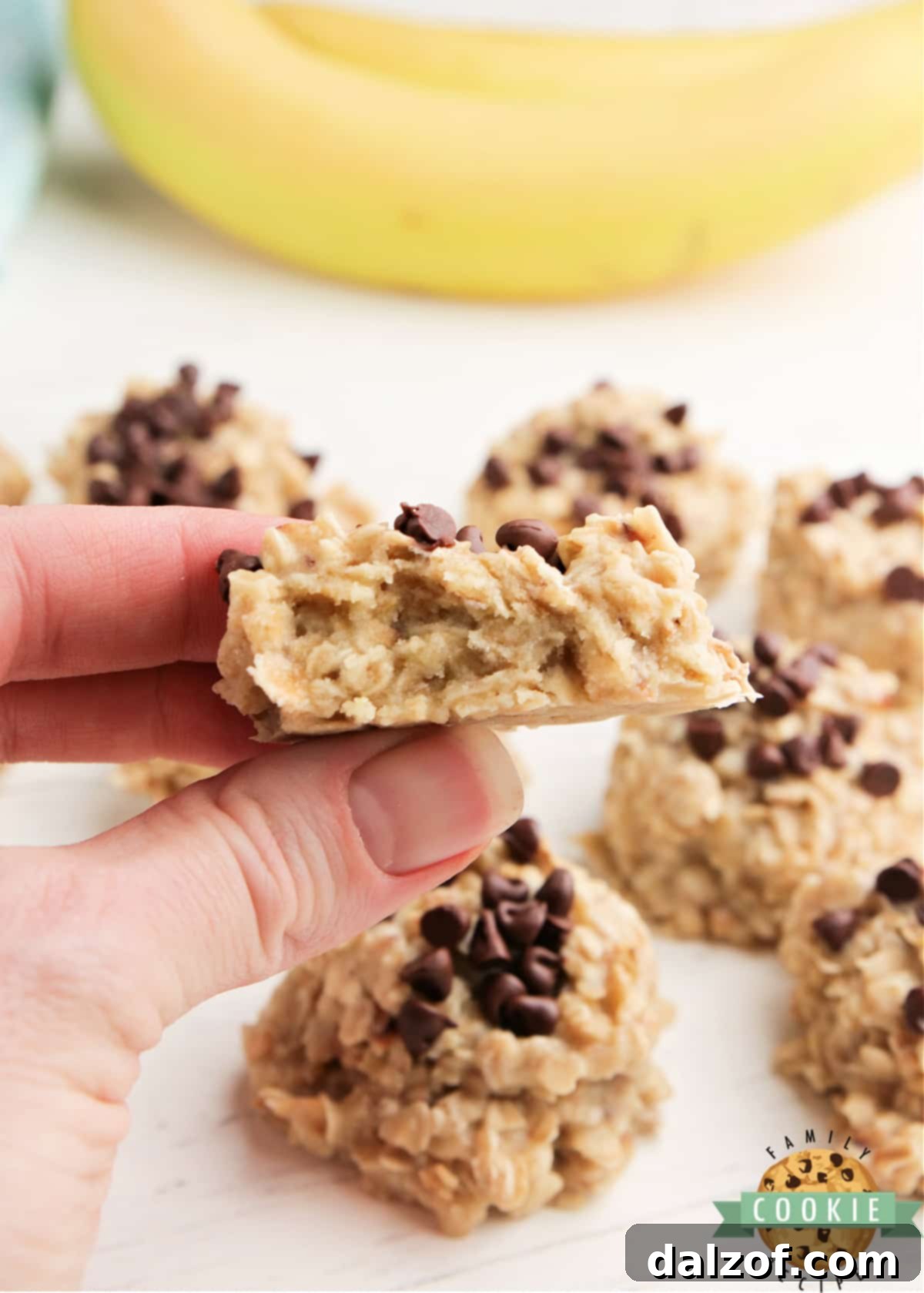 A close-up of a single banana no-bake cookie with a bite taken out, showing its chewy interior.