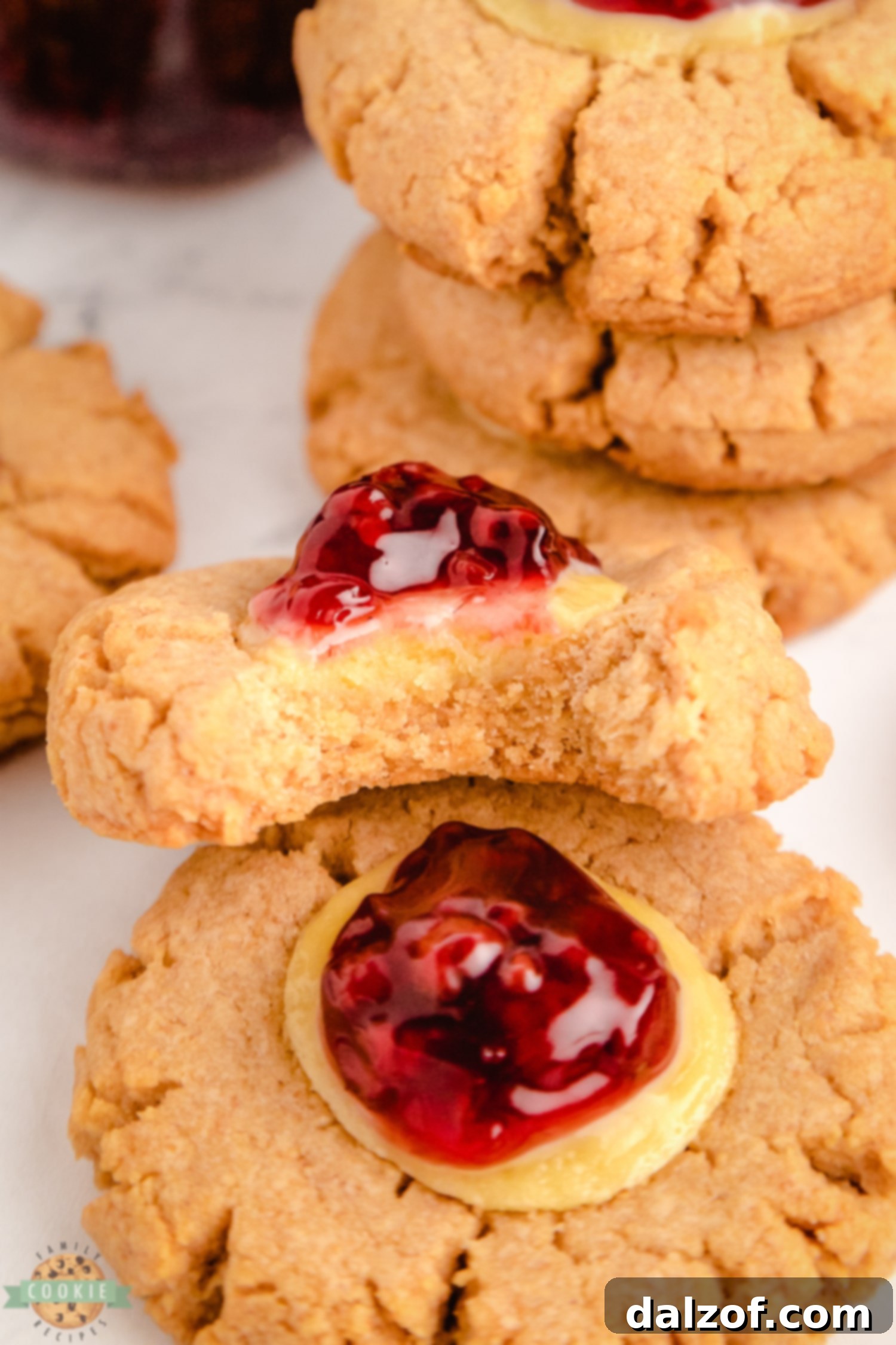 A perfectly baked raspberry cheesecake cookie with a bite taken out, revealing the creamy filling and graham cracker base.