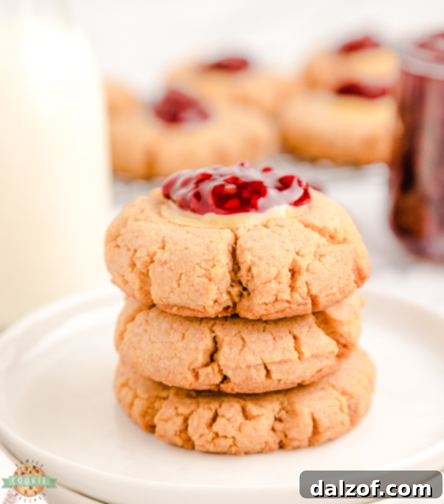 A stack of three beautifully decorated raspberry cheesecake cookies, showcasing their golden base, creamy filling, and vibrant topping.