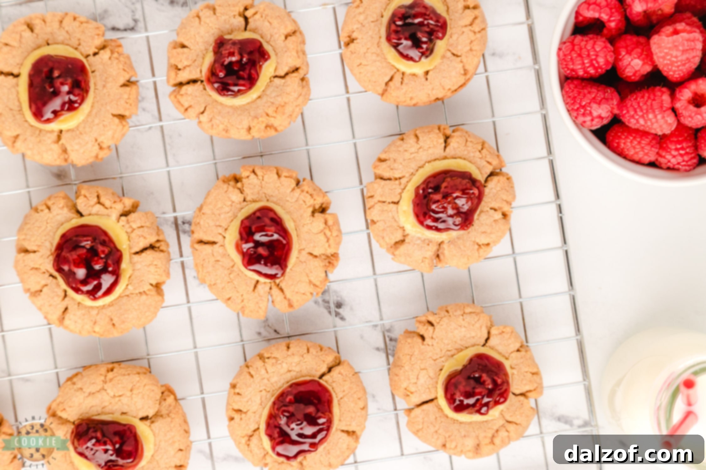 Freshly baked raspberry cheesecake cookies cooling on a wire rack.