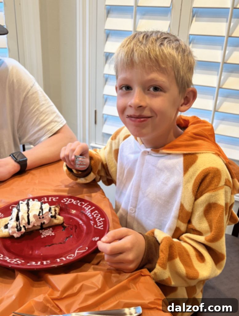 Child in giraffe costume eating crepes on 'You Are Special' plate