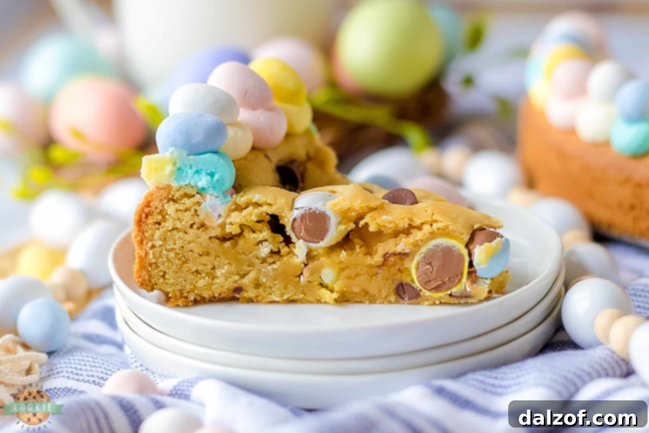 A close-up of the Easter cookie cake, showcasing the vibrant pastel buttercream and colorful mini Cadbury eggs scattered generously across the top, ready for a slice.