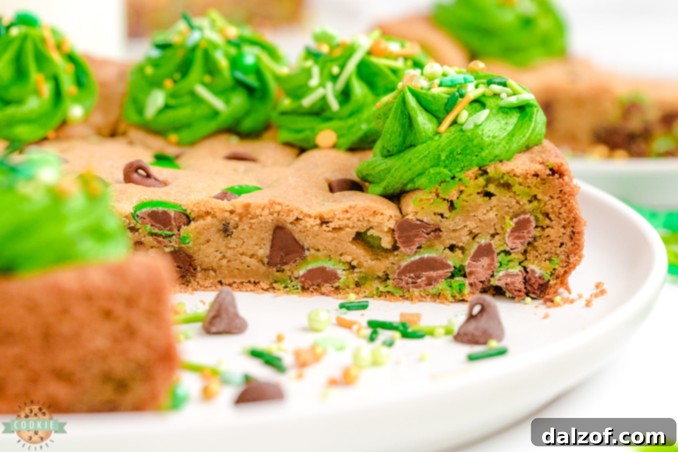 A beautifully sliced St. Patrick's Day cookie cake with green frosting and candies