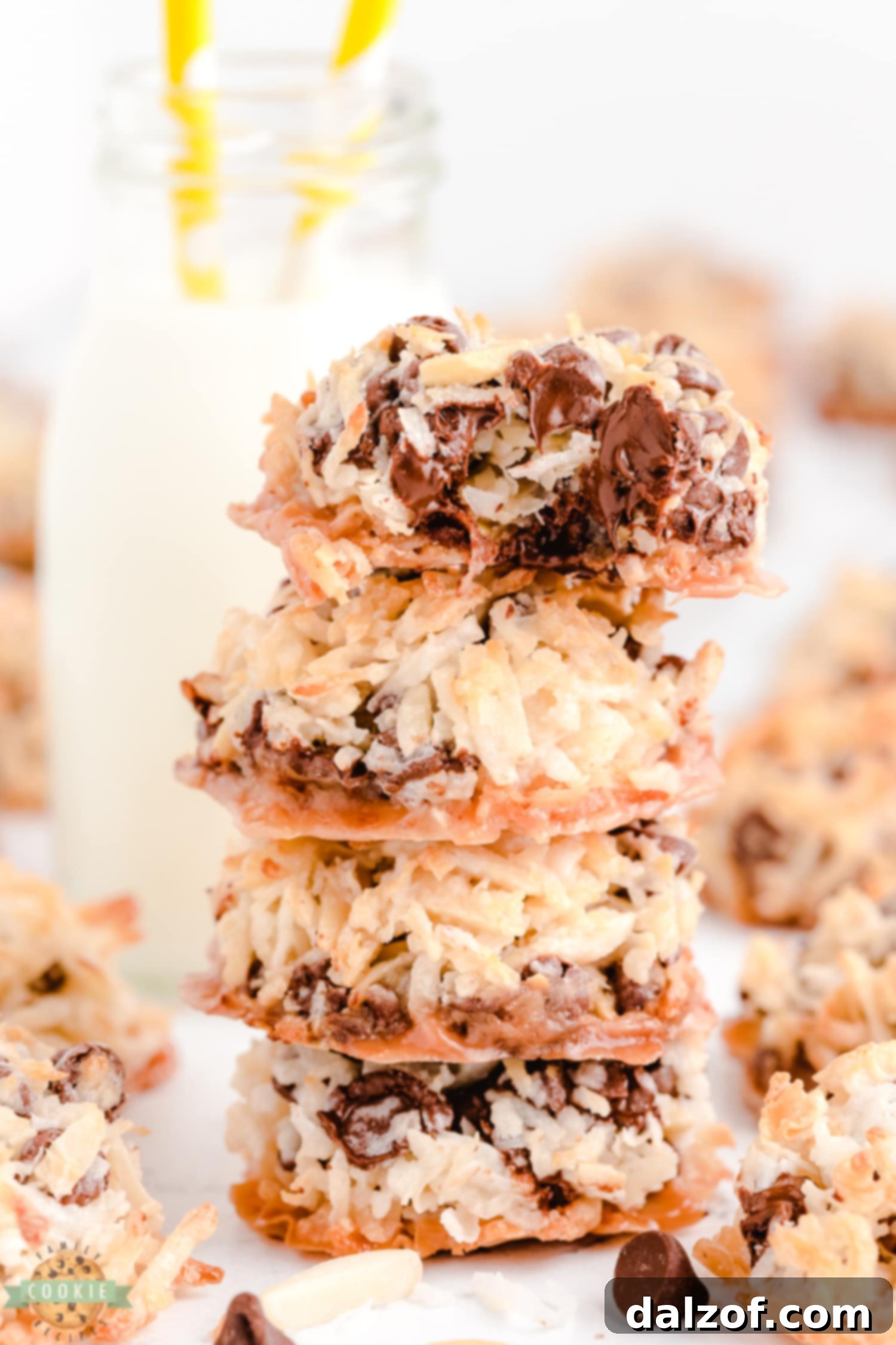 A close up shot of a person biting into an Almond Joy cookie, showing the coconut, chocolate, and almond textures