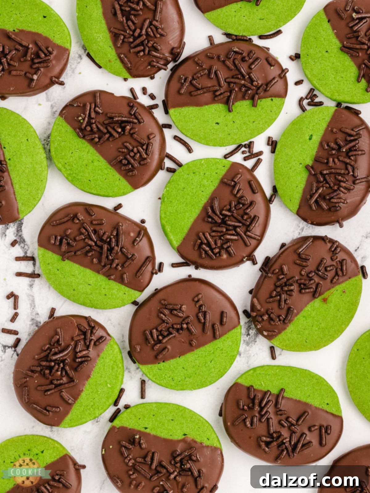 Green mint shortbread cookies dipped in chocolate, laid out on wax paper.