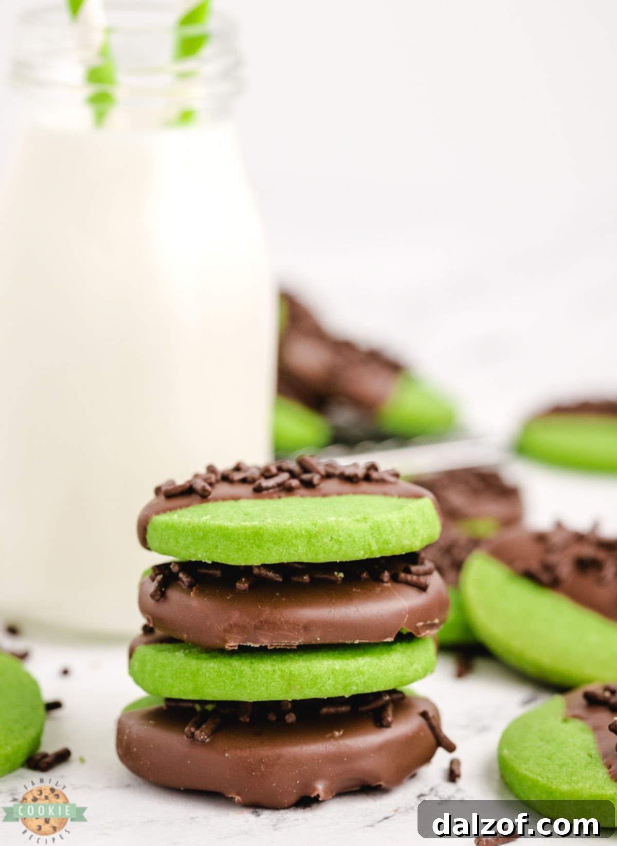 Stack of green shortbread cookies with a glass of milk.
