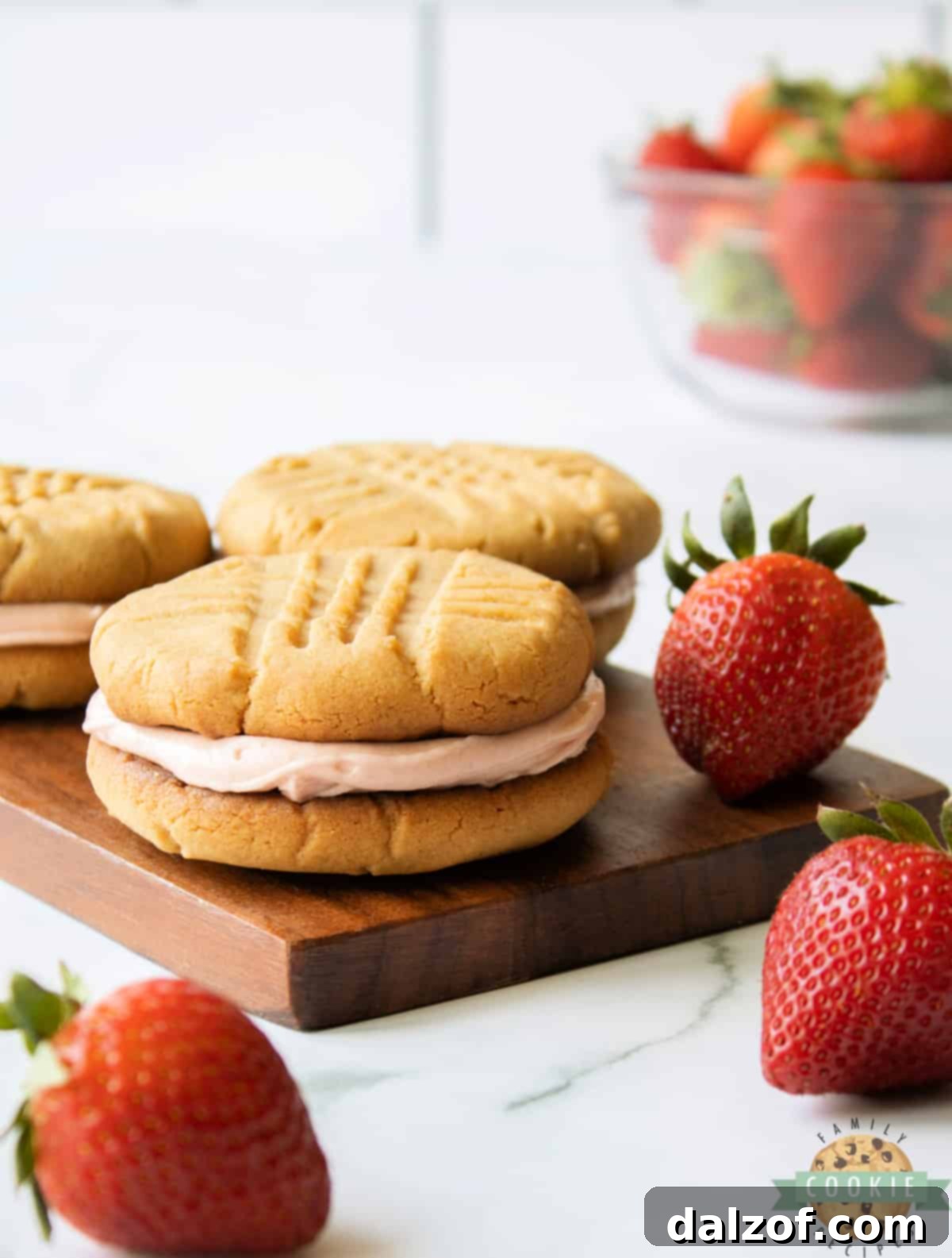 Close-up of a Peanut Butter and Jelly Sandwich Cookie, revealing the creamy strawberry buttercream filling between two soft peanut butter cookies.