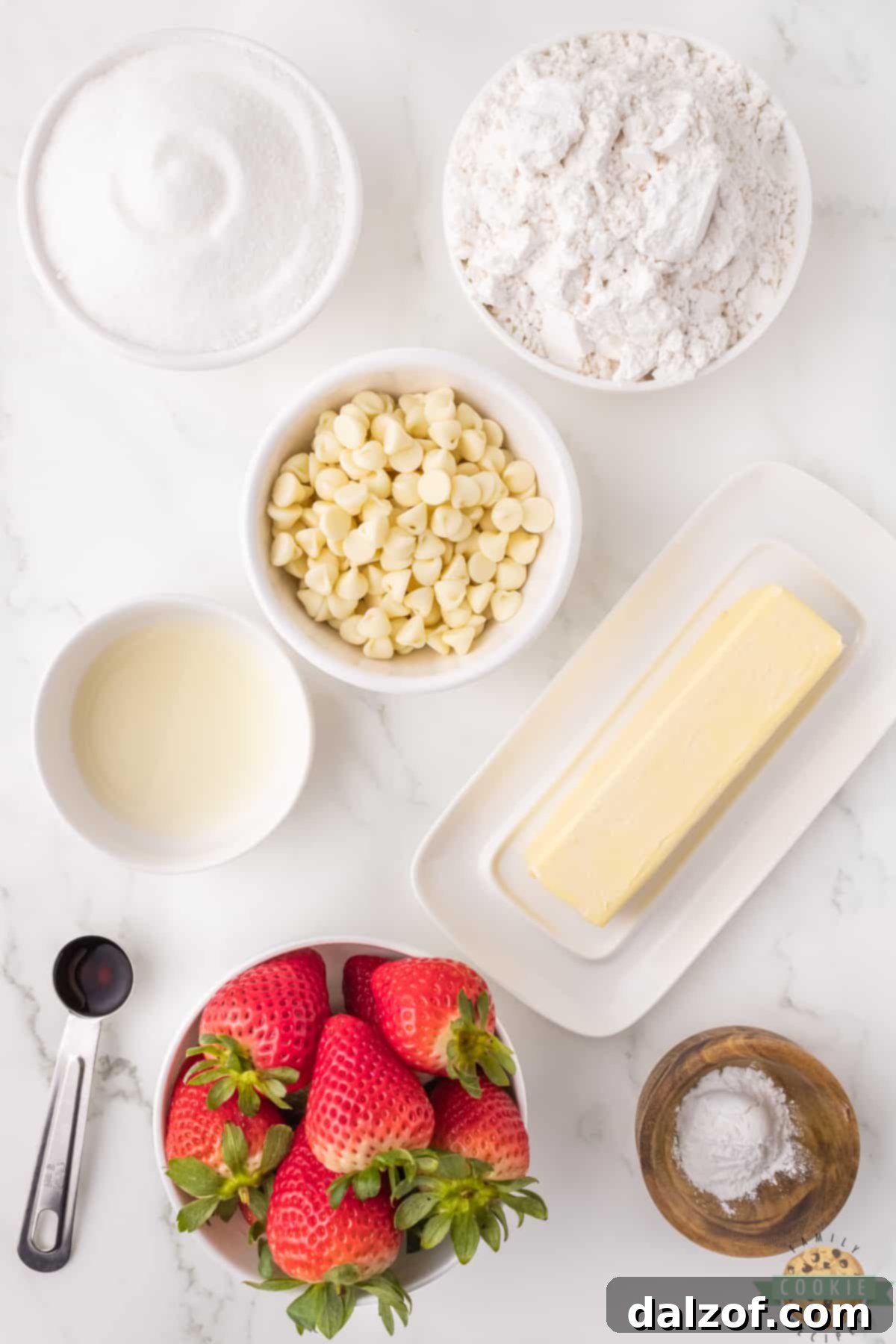 A collection of fresh ingredients laid out, including butter, sugar, flour, baking powder, vanilla, lemon, white chocolate chips, and fresh strawberries, ready for making strawberry cookies.