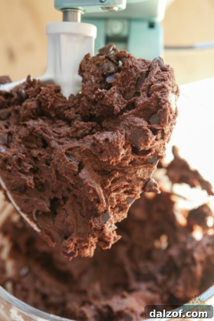 Folding semi-sweet chocolate chips into rich double chocolate pudding cookie dough for ultimate flavor.