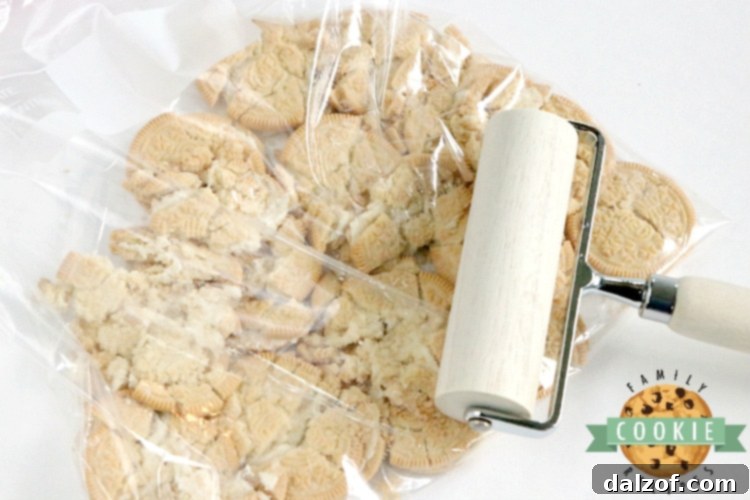 A hand demonstrating how to crush Golden Oreo cookies inside a resealable plastic bag.