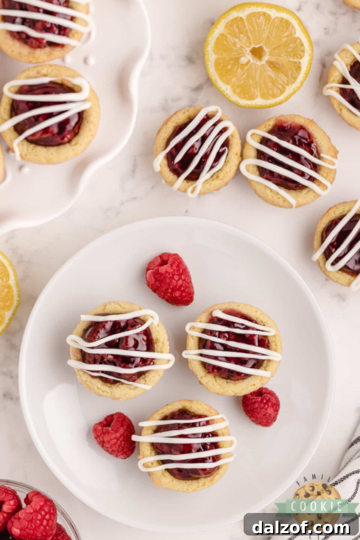 Lemon Raspberry Cookie Cups are made with a simple lemon cookie recipe and raspberry pie filling. Drizzle a little white chocolate on top for a bite sized cookie cup recipe that is impressive and delicious!