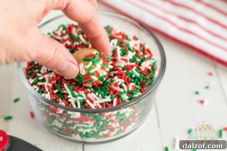 rolling sugar cookies in Christmas jimmies sprinkles