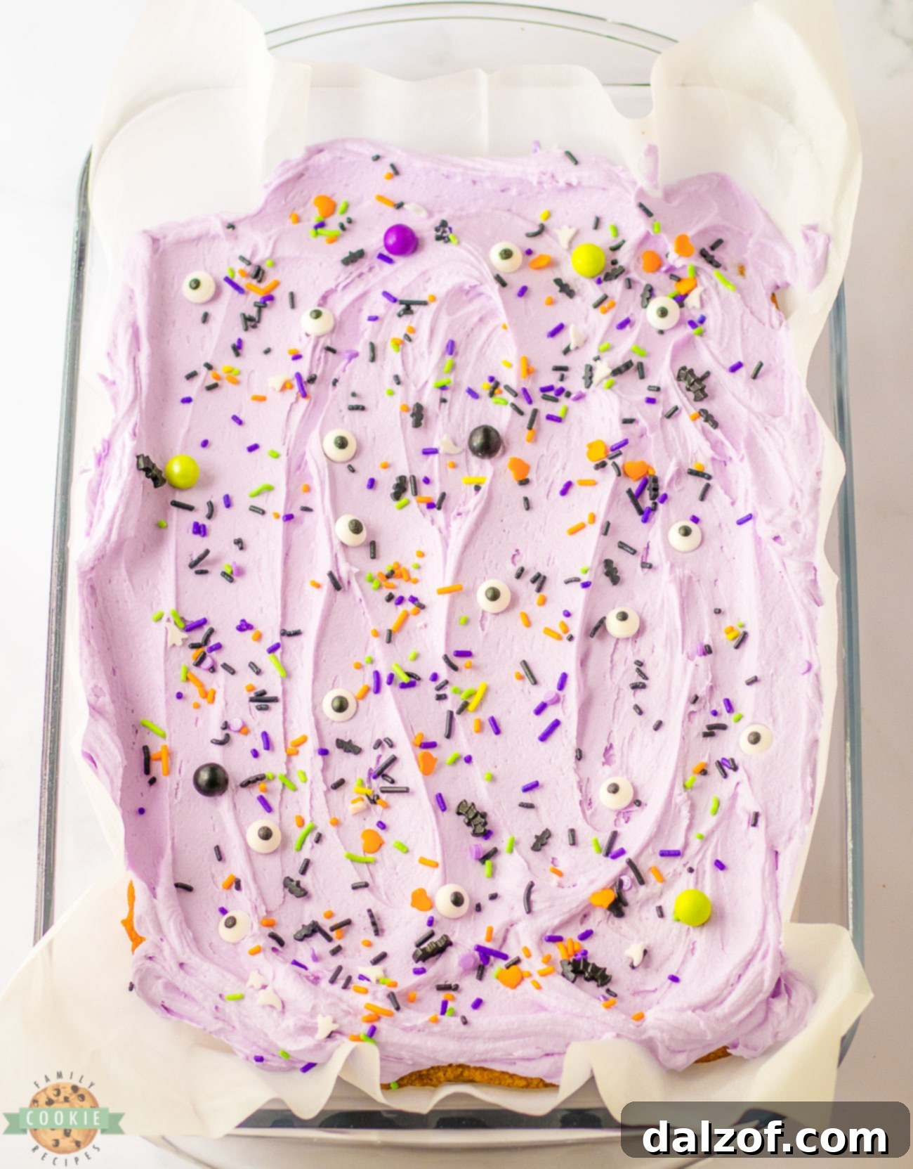A full pan of freshly frosted Halloween Sugar Cookie bars with vibrant purple buttercream and colorful sprinkles.