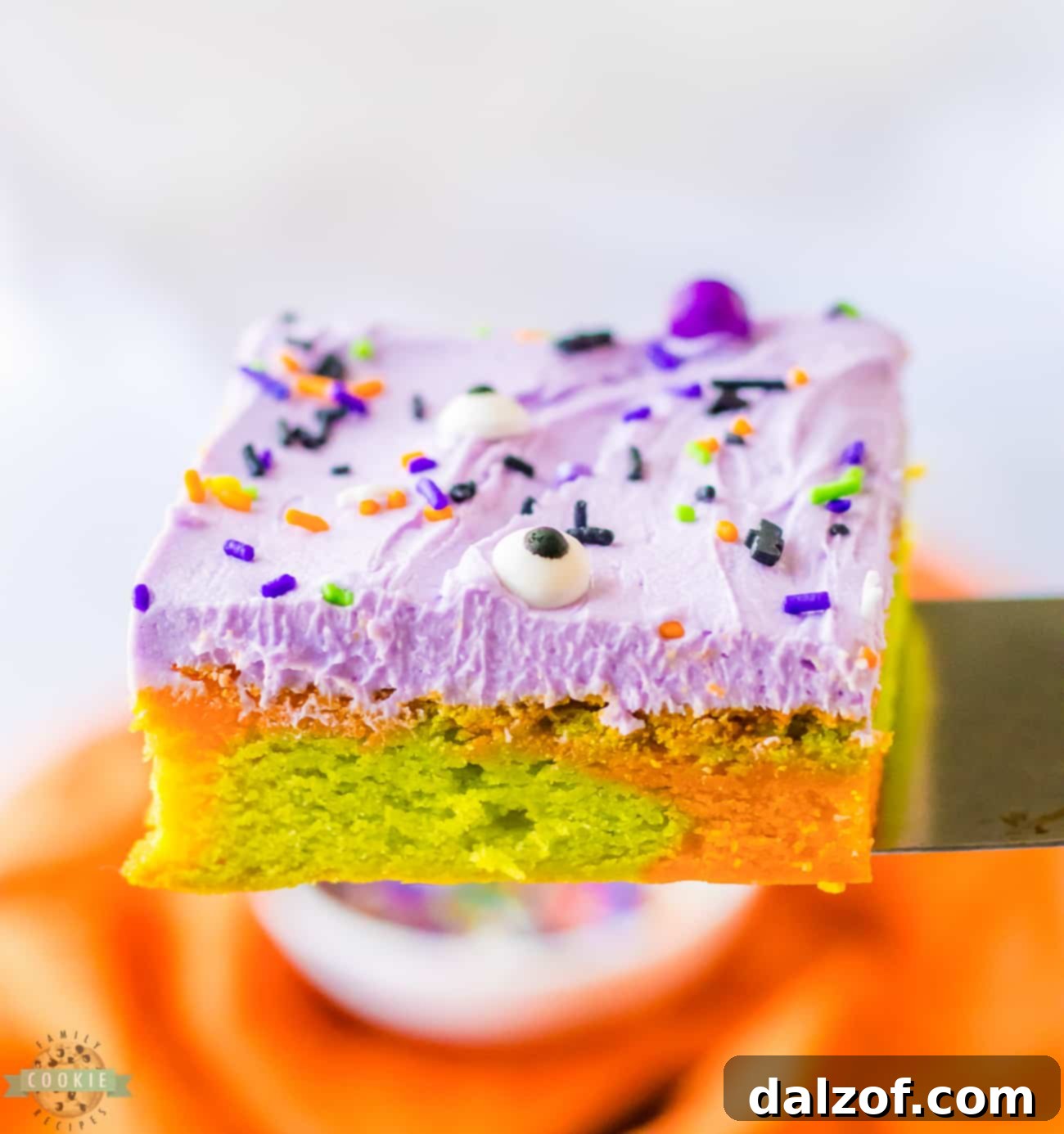 A plate of Halloween sugar cookie bars topped with rich purple frosting and festive sprinkles, ready to serve.