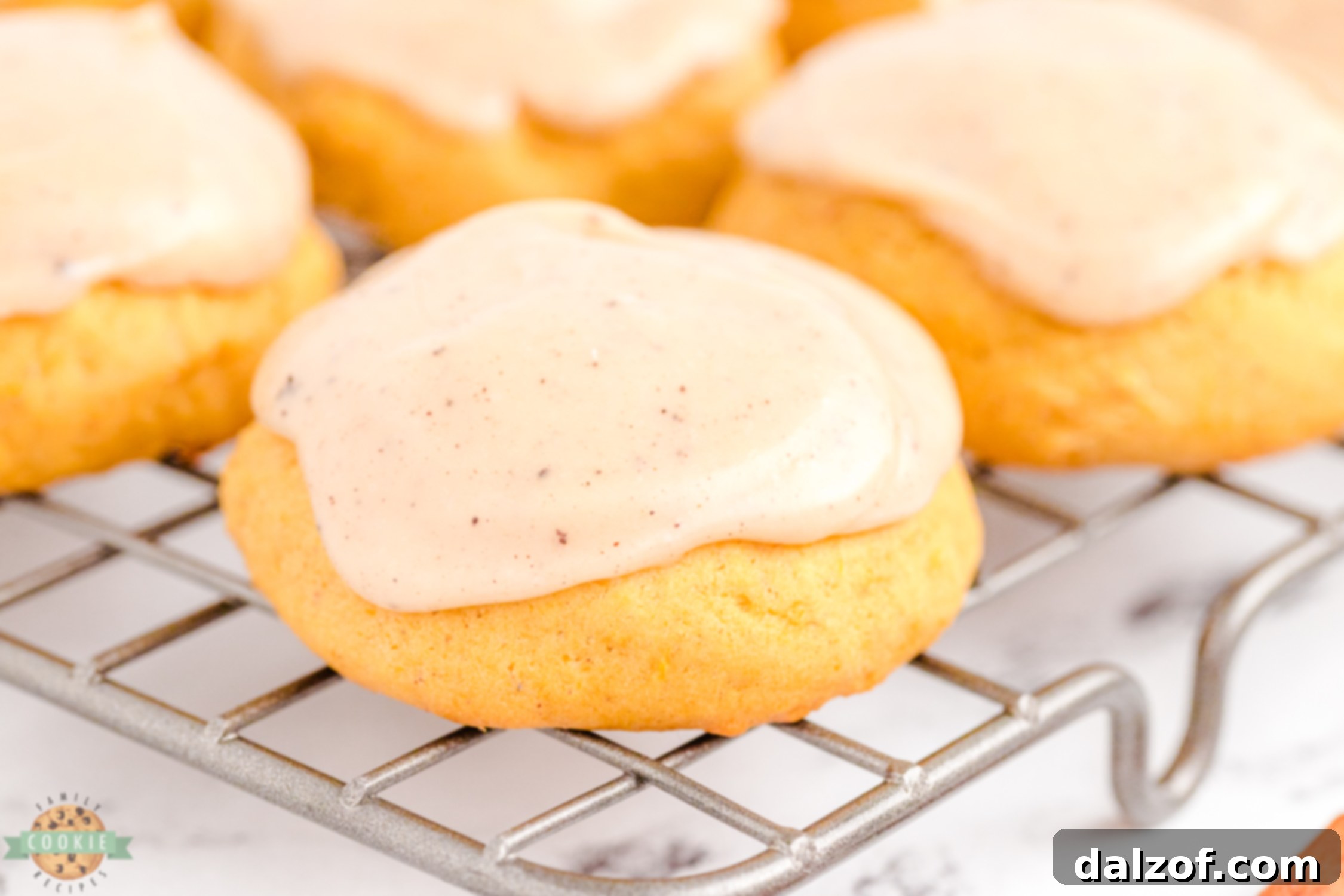 frosted pumpkin cookie on a cooling rack