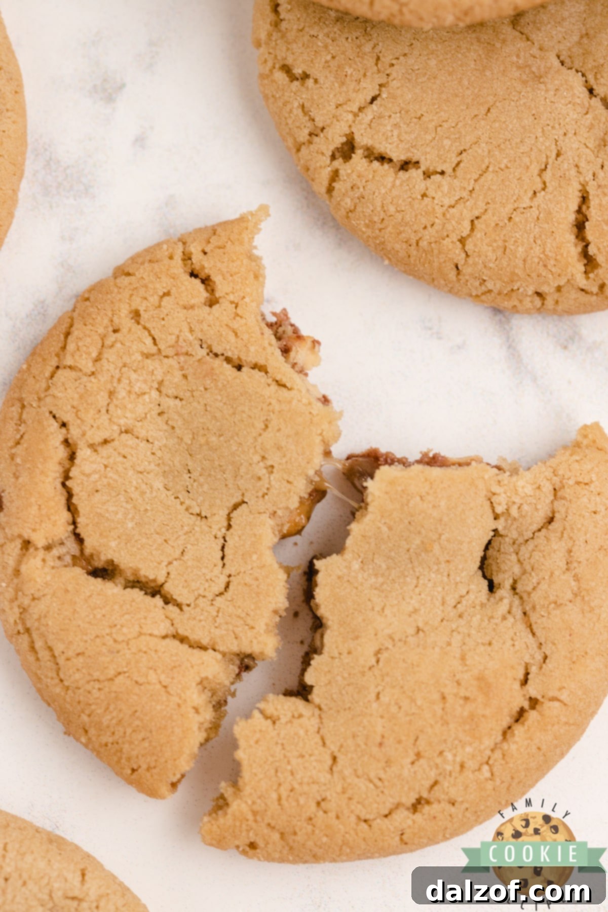 Freshly baked peanut butter cookies, some showing a peek of the mini Snickers inside