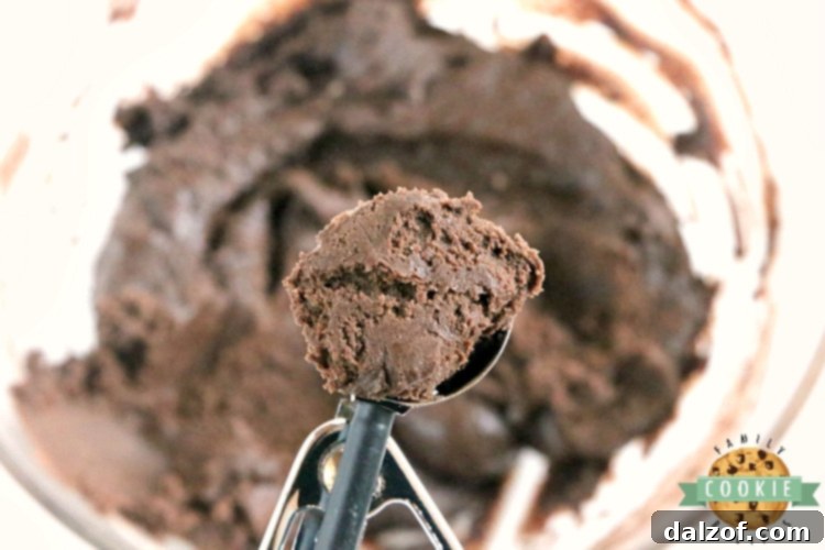 Scooping cake mix cookie dough onto a baking sheet for Chocolate Peppermint Blossoms