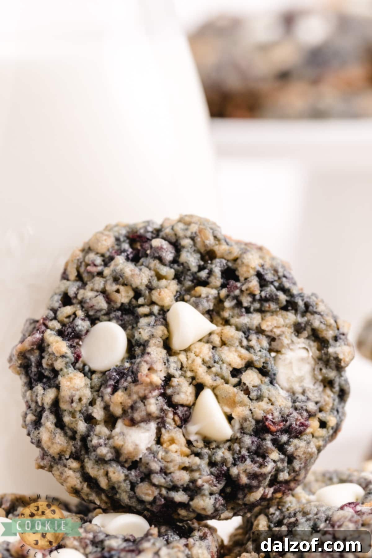 Freshly baked oatmeal cookies with white chocolate chips and blackberries on a cooling rack.