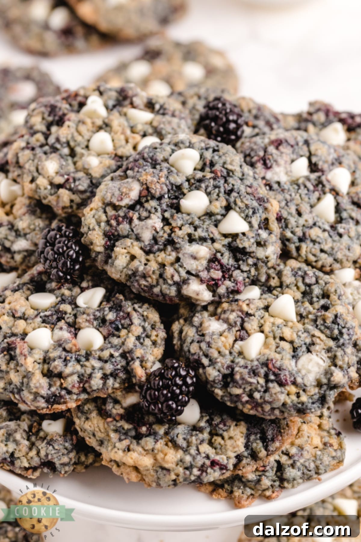 Overhead view of several golden brown oatmeal cookies with blackberries scattered, emphasizing their fresh and homemade quality.