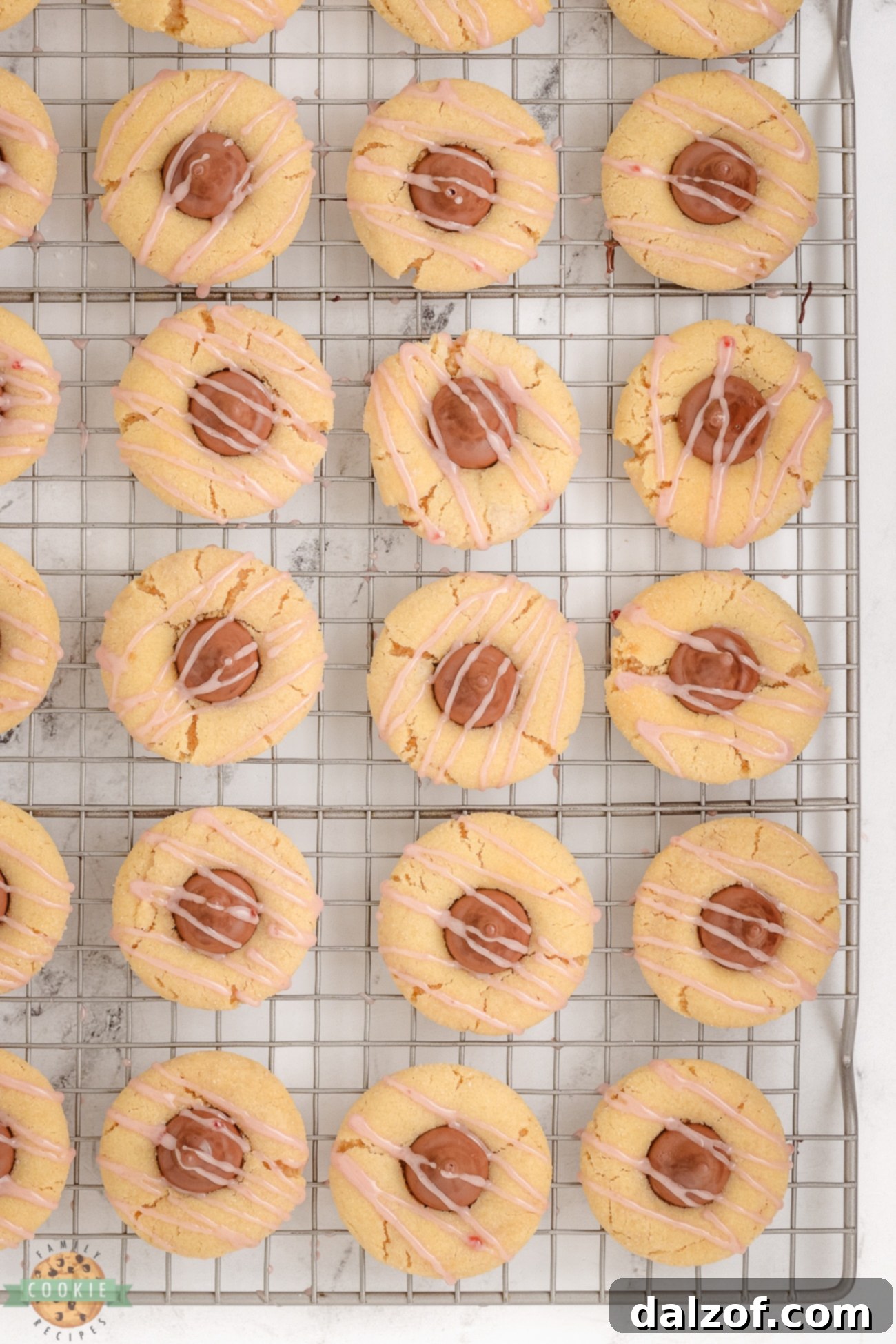 Raspberry Almond Kiss Cookies cooling on a wire rack with chocolate kisses and pink glaze