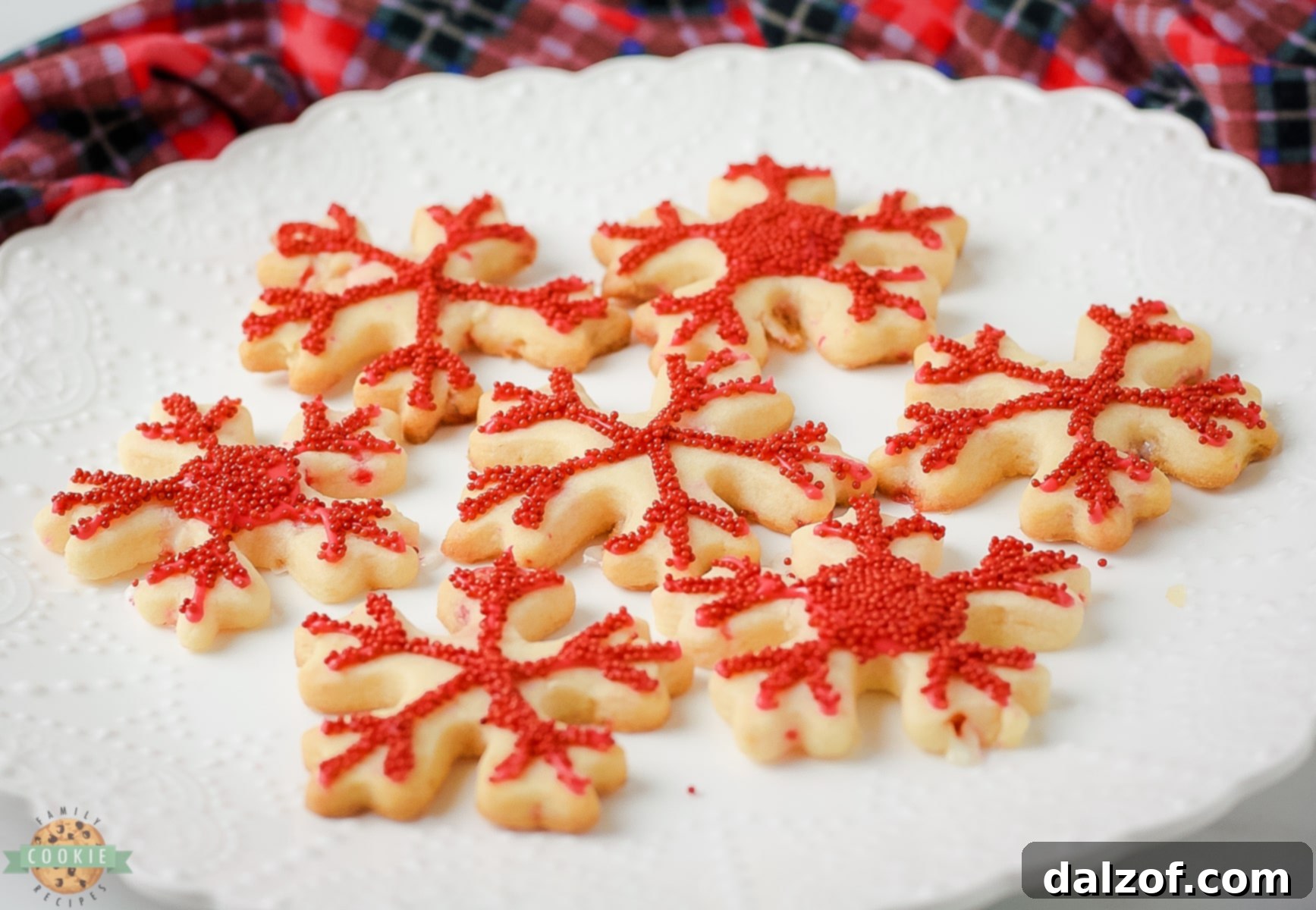 A plate piled high with festive Peppermint Cut Out Cookies, adorned with glaze and candy cane sprinkles.