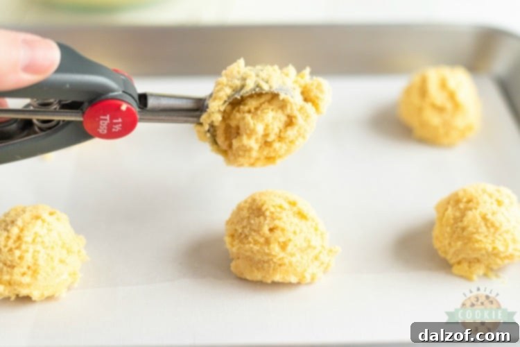 Close-up of raw lemon jello sugar cookie dough balls on a baking sheet, pressed flat and sugar-coated