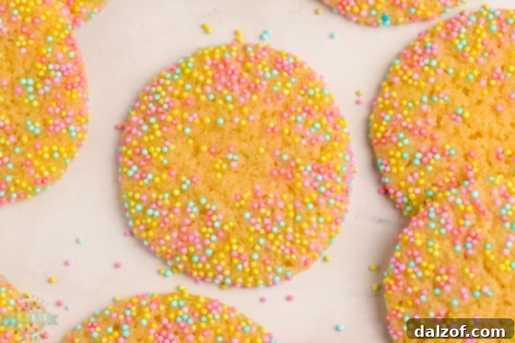 Freshly baked Easter sprinkle cookies cooling on parchment paper on a wire rack.