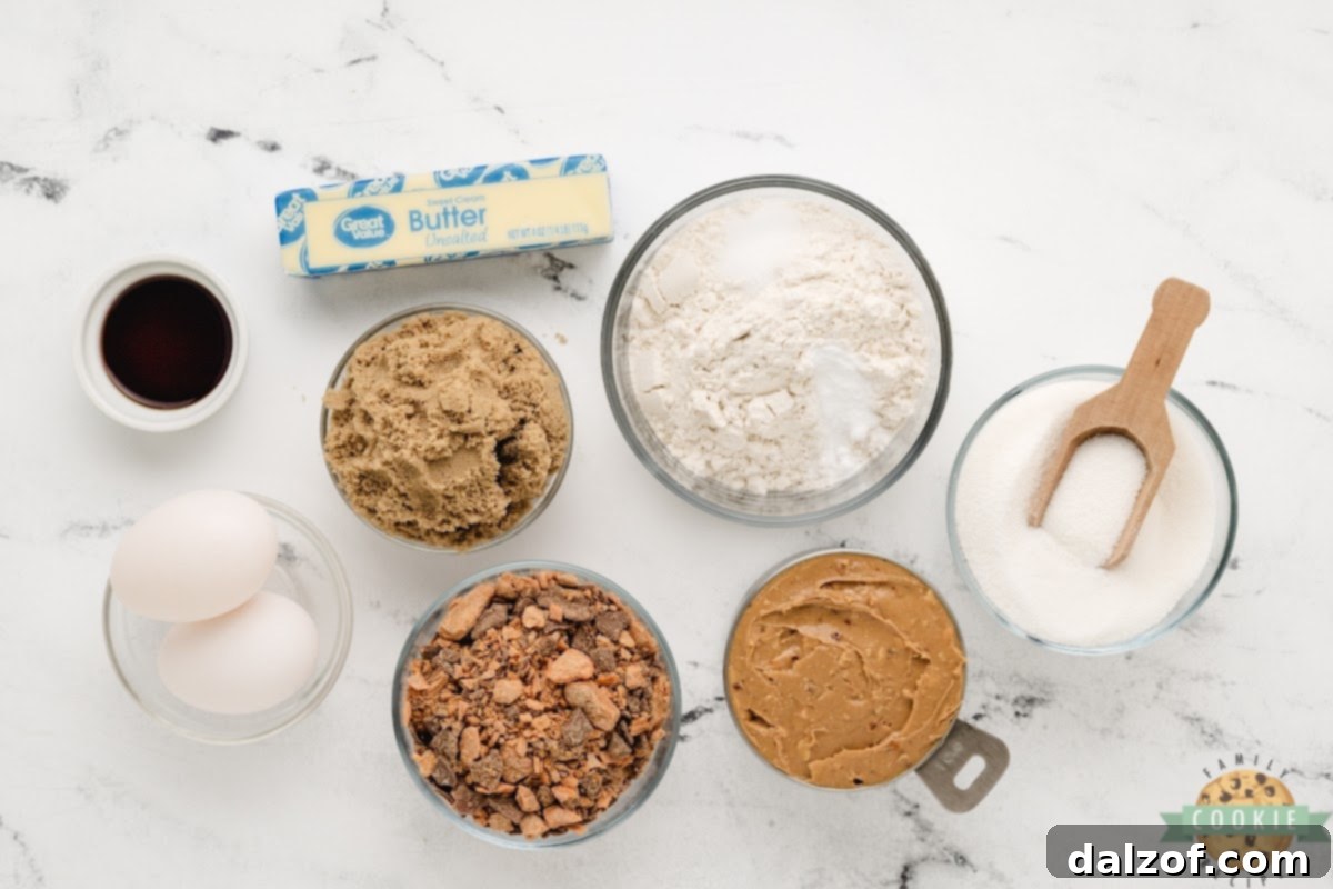 Arrangement of ingredients for Butterfinger Peanut Butter Cookies, including butter, sugars, peanut butter, and Butterfinger candy.