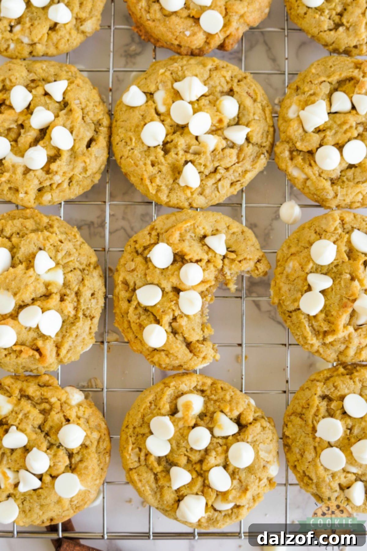 Warm pumpkin cookies cooling on a wire rack, featuring oats and melted white chocolate chips.