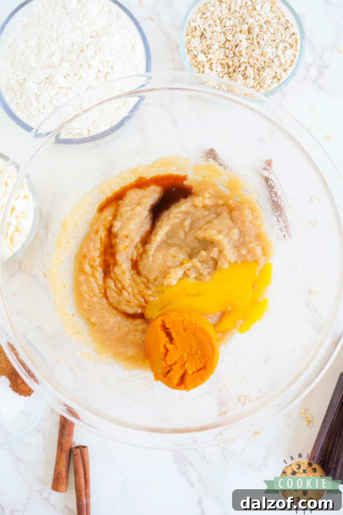 Adding pumpkin puree, egg yolk, and vanilla extract to the creamed butter and sugar mixture.