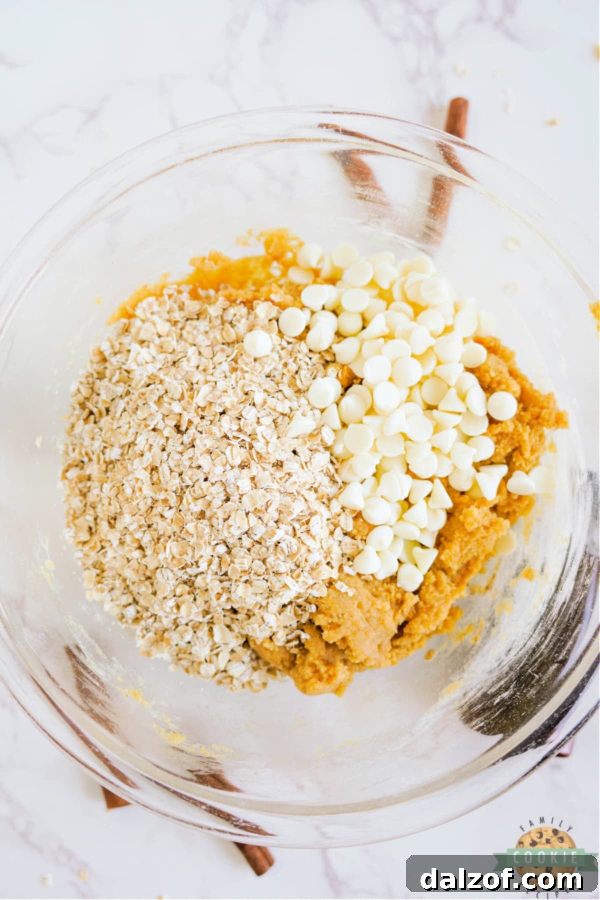 Adding quick oats and white chocolate chips to the pumpkin cookie dough.