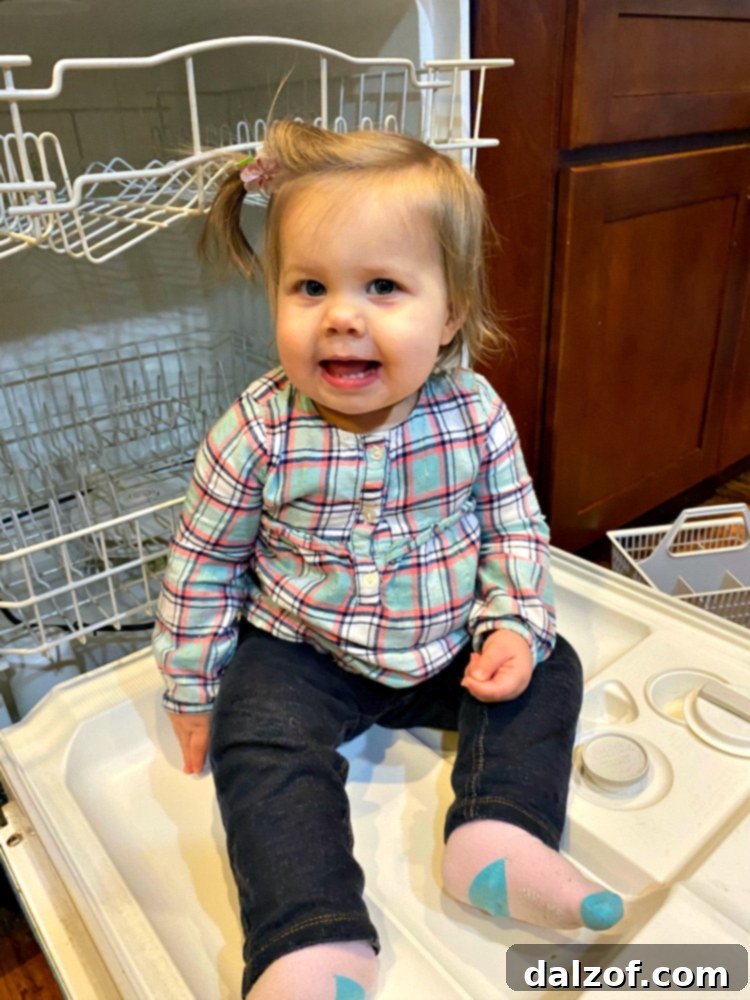 A toddler girl smiling, sitting next to a bowl of cookie ingredients, representing family baking and the joy of homemade treats.